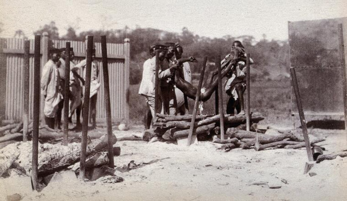 Figure 7: A group of men lower the body of a dead man onto a pyre of logs prior to a Hindu cremation ceremony in Bombay at the time of the plague. Photograph, 1896/1897. Wellcome Collection. Public Domain Mark