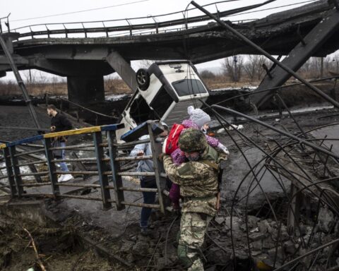 A Ukrainian commander carried a young girl as he helped people flee across a destroyed bridge on the outskirts of Kyiv, Ukraine, on Thursday. A Ukrainian commander carried a young girl as he helped people flee across a destroyed bridge on the outskirts of Kyiv, Ukraine, on Thursday.HEIDI LEVINE/FTWP